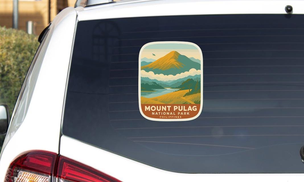 A sticker on the rear window of a car that says "Mount Pulag National Park Philippines".