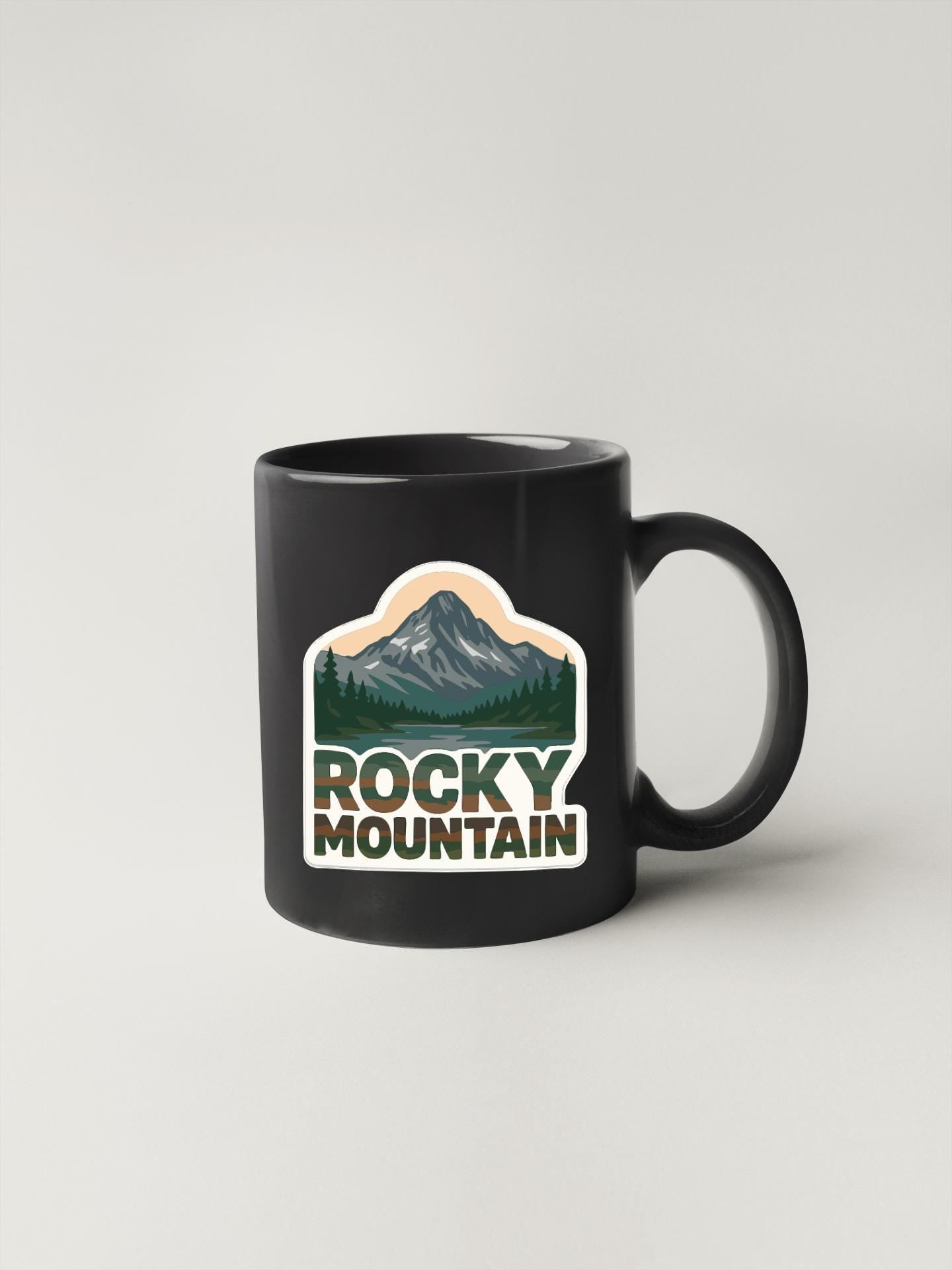 A black coffee mug with a mountain landscape sticker on it.