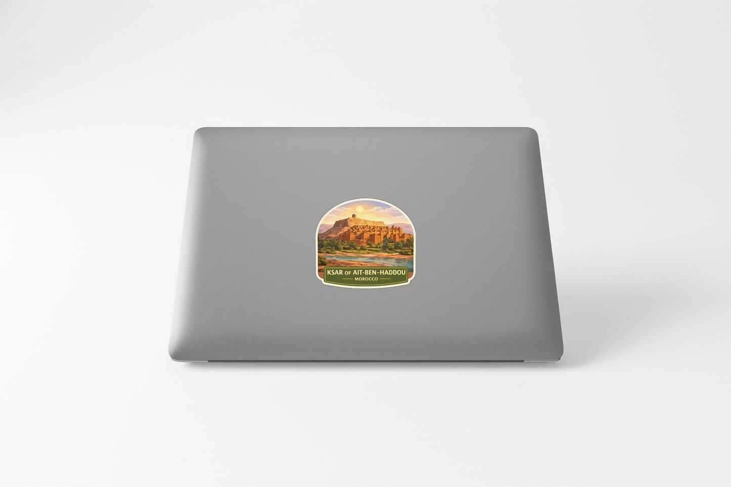 A sticker depicting a scenic landscape with a mountain and a body of water, placed on the back of a laptop computer.