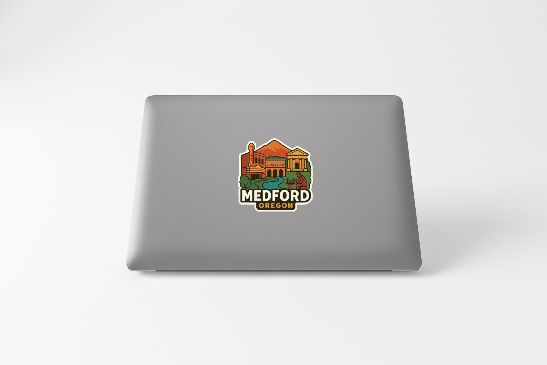 a sticker with an illustration of a cityscape and the text "MEDFORD OREGON" on the back of a laptop.