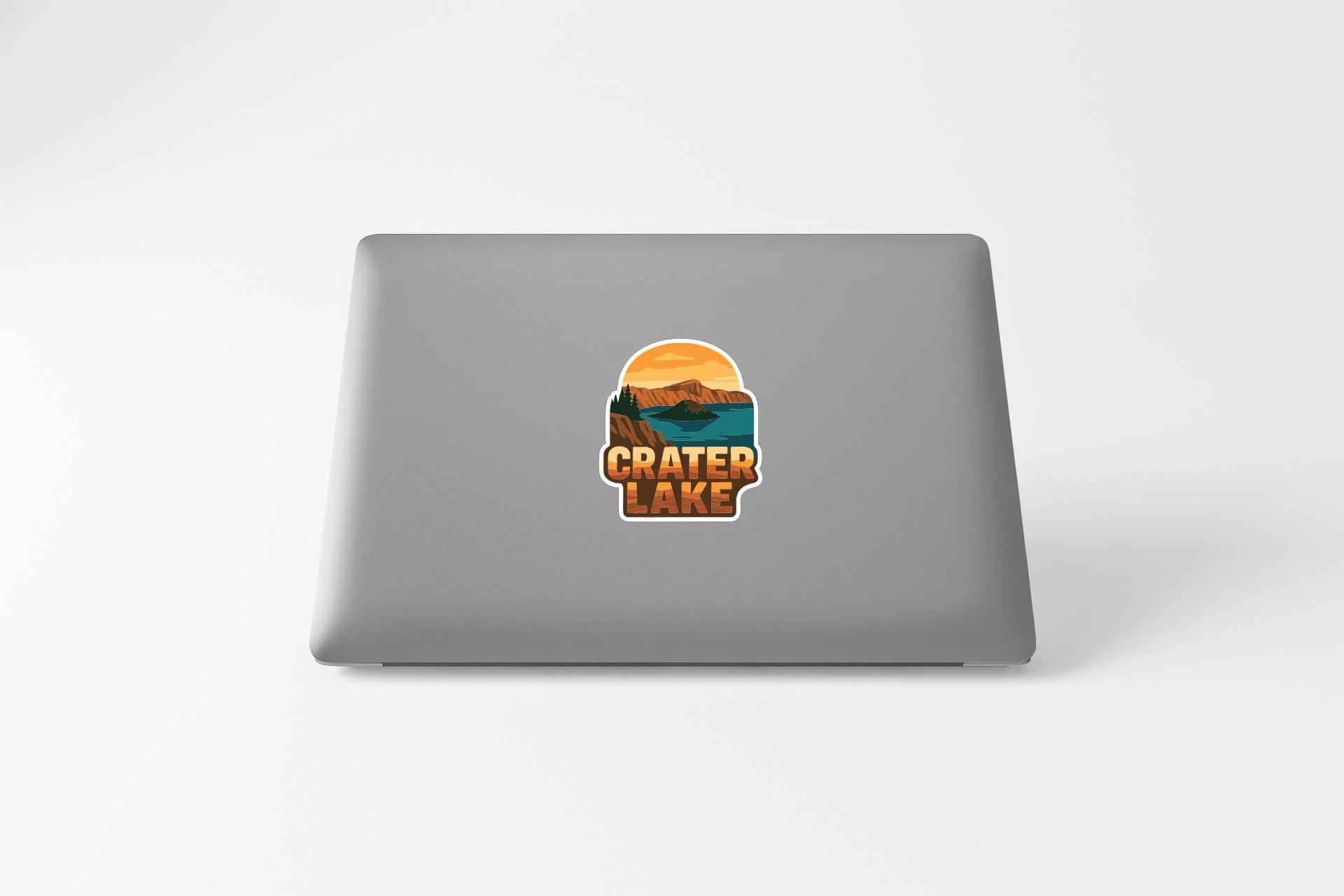A sticker on the back of a laptop displaying the text "CRATER LAKE" along with an illustration of a scenic landscape.