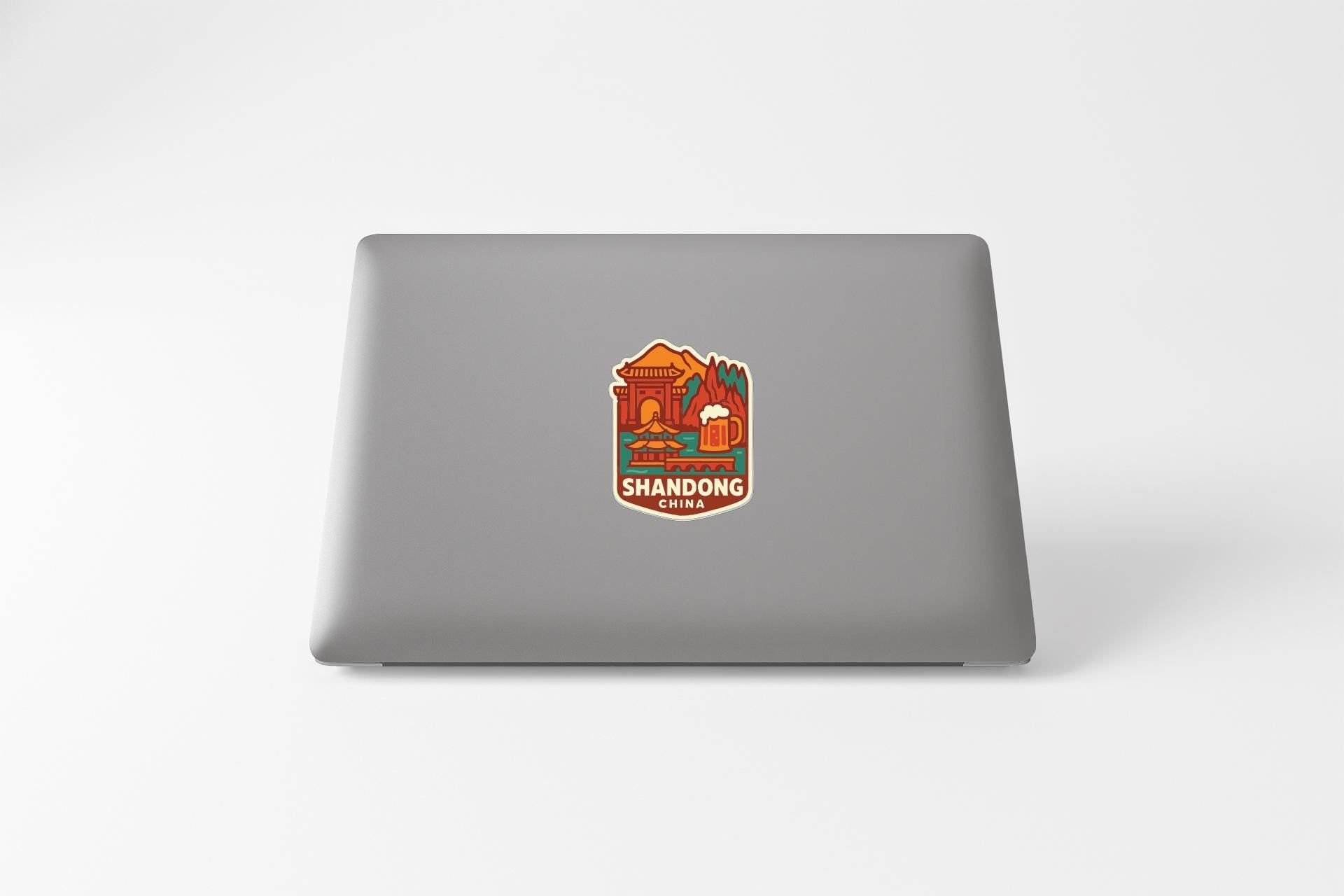 a sticker with an illustration of a building and a beer mug, along with the text "SHANDONG CHINA" printed on it.