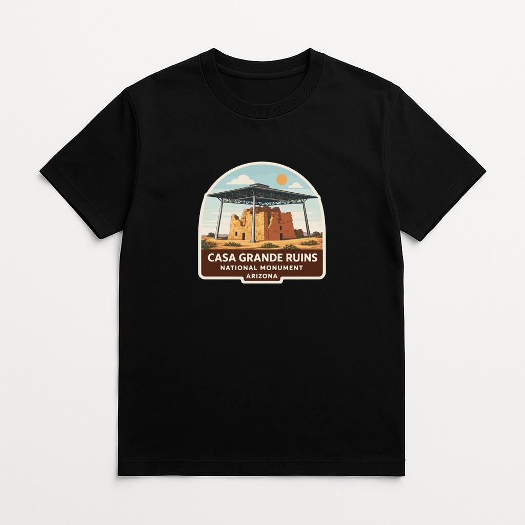 A black t-shirt with a graphic design depicting the Casa Grande Ruins National Monument in Arizona.