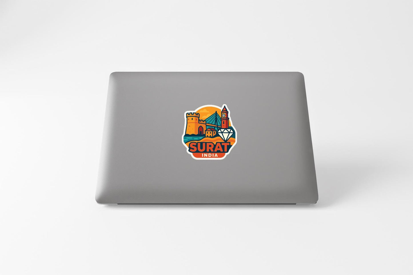 a sticker with a cityscape and the word "SURAT" on the back of a laptop.