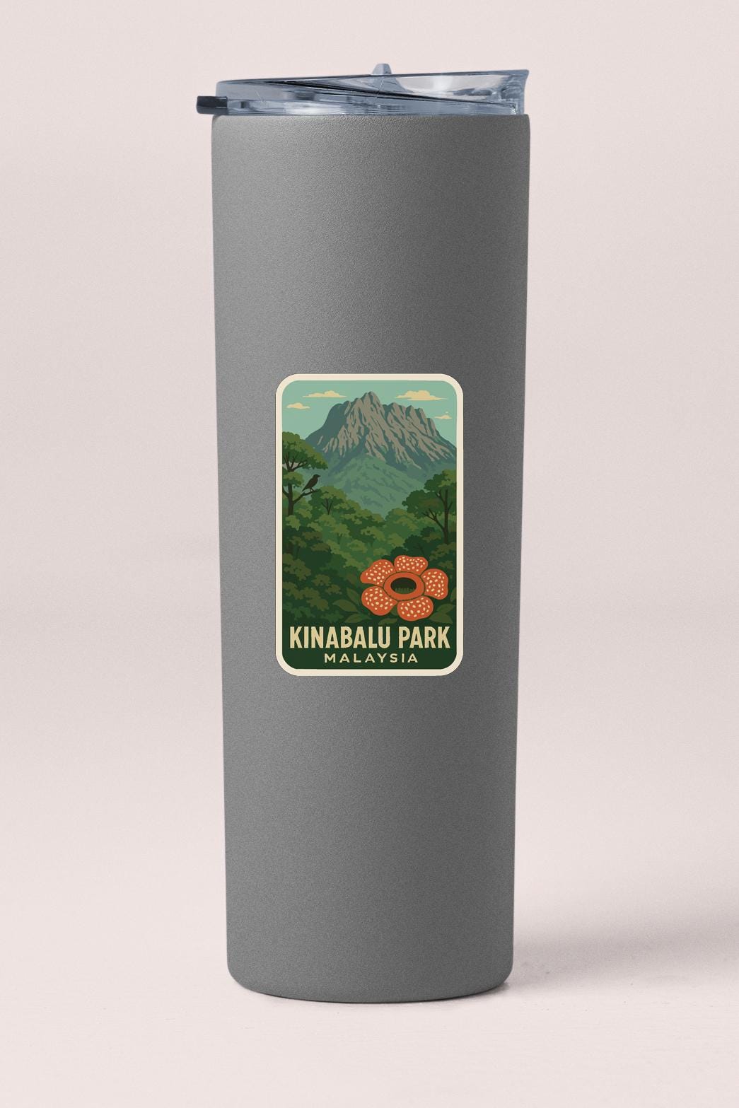 A gray cylindrical container with a sticker depicting a mountain landscape and a flower.