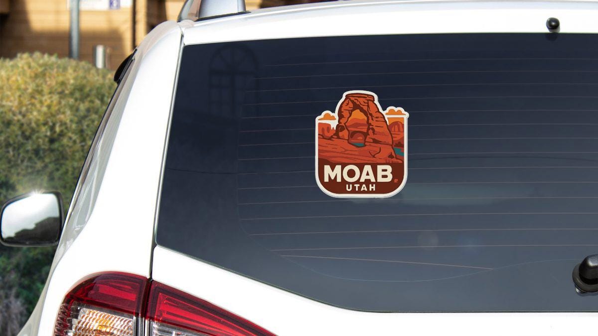A sticker of Moab Utah on the rear window of a white vehicle.