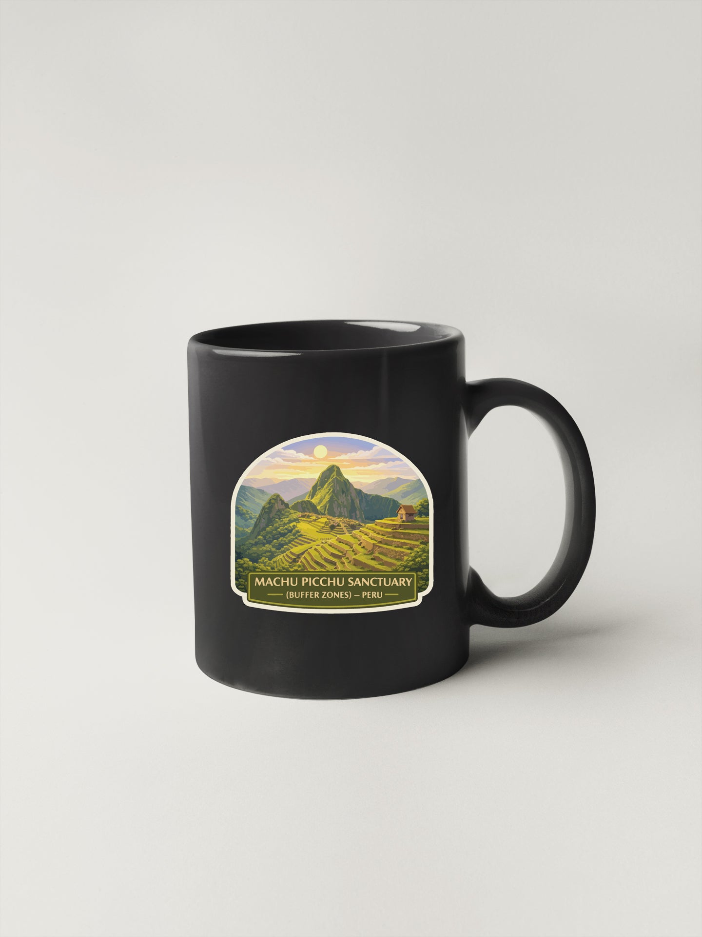 A black coffee mug with a label depicting the Machu Picchu Sanctuary in Peru.