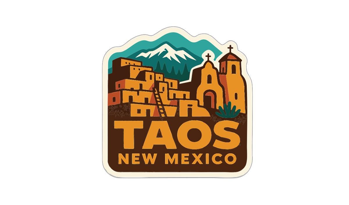 A sticker or label featuring a stylized illustration of a town or village with mountains in the background, along with a church or cathedral. The text "TAOS NEW MEXICO" is prominently displayed in the center of the image.
