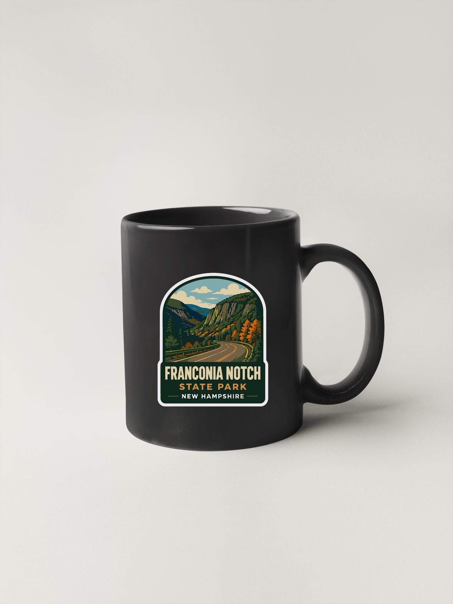 A black coffee mug with a label that says "FRANCOMIA NOTCH STATE PARK NEW HAMPSHIRE".