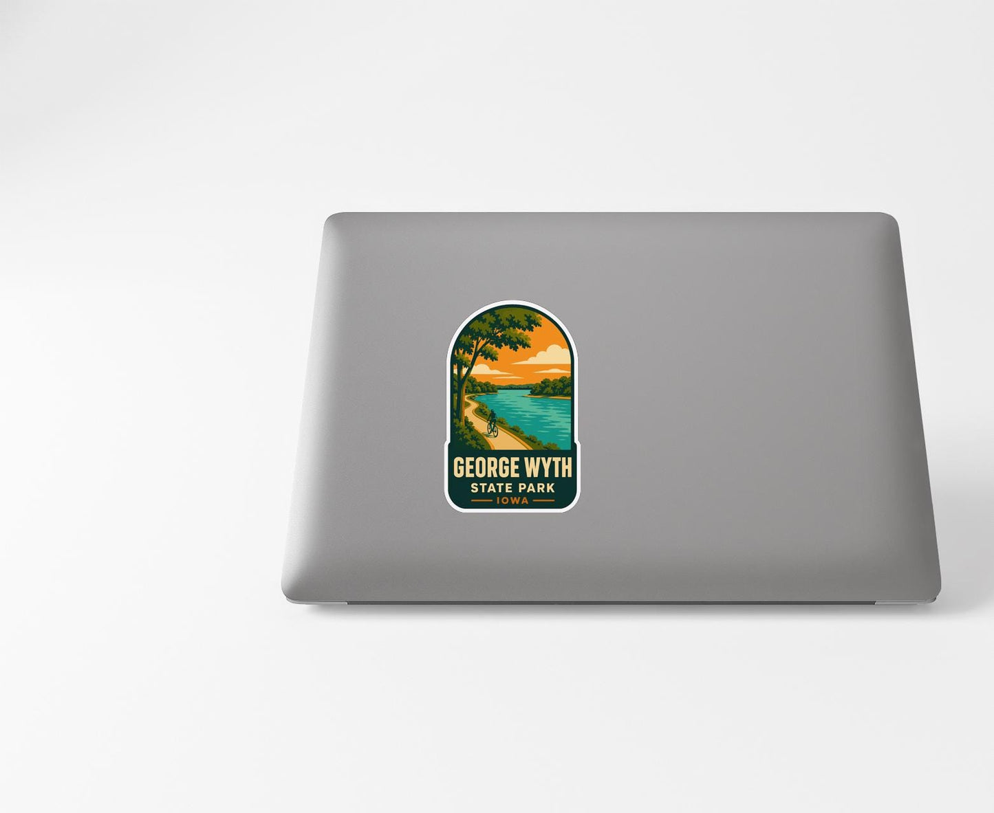 A sticker on the back of a laptop displaying a scenic landscape with a lake and trees.