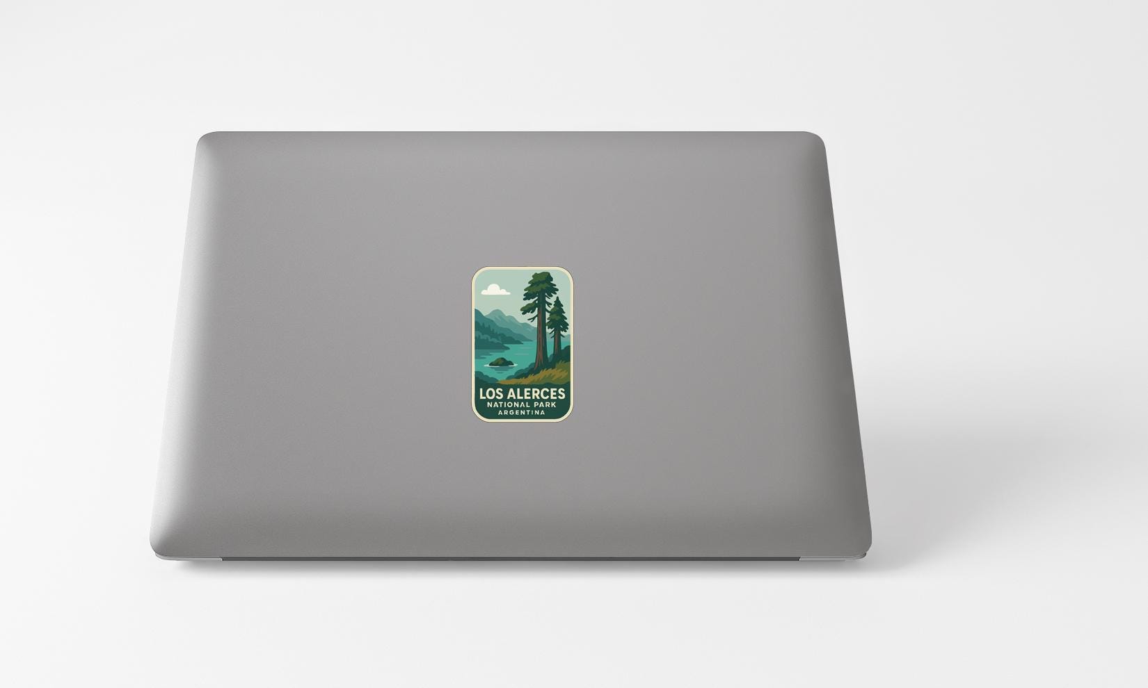 A sticker with a landscape image and text on the back of a laptop computer.