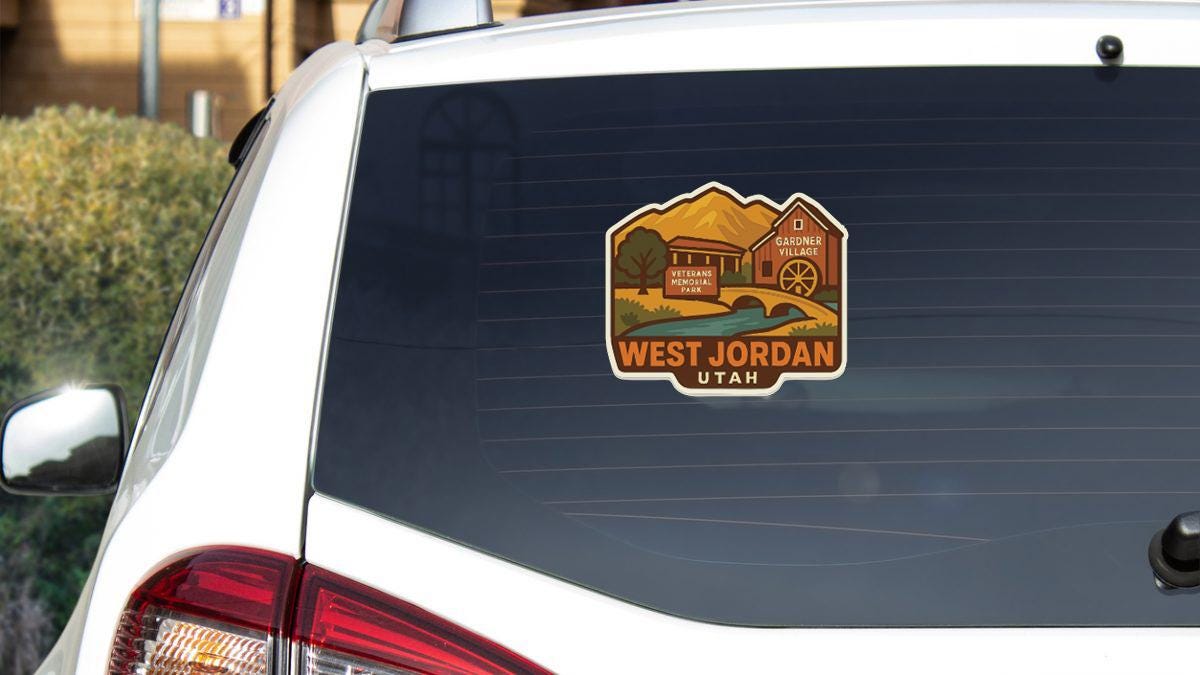 A sticker on the rear window of a white vehicle, depicting a scenic landscape with mountains and a building, indicating the location of West Jordan, Utah.