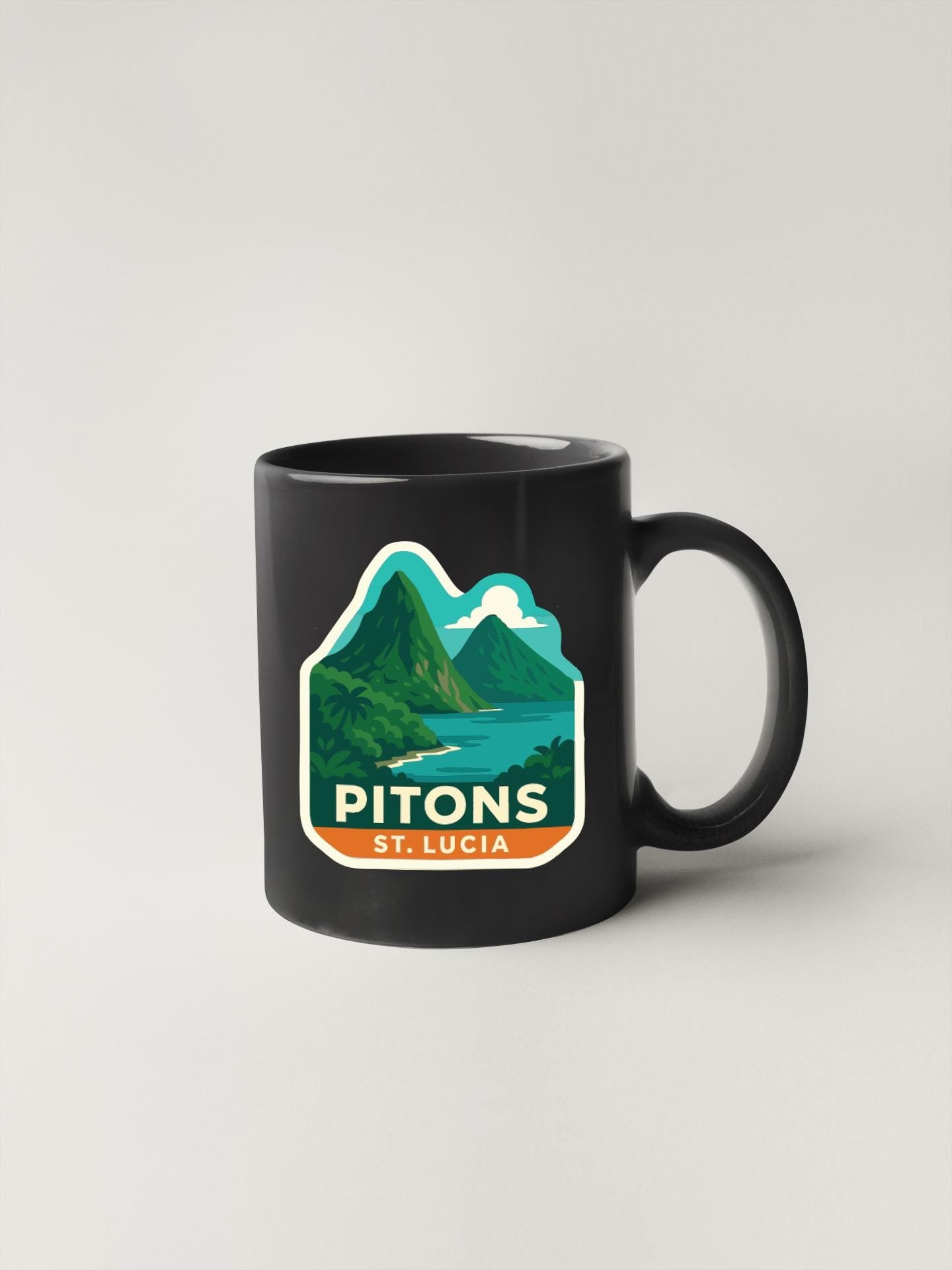 A black coffee mug with a graphic design depicting a mountainous landscape with a lake and palm trees.