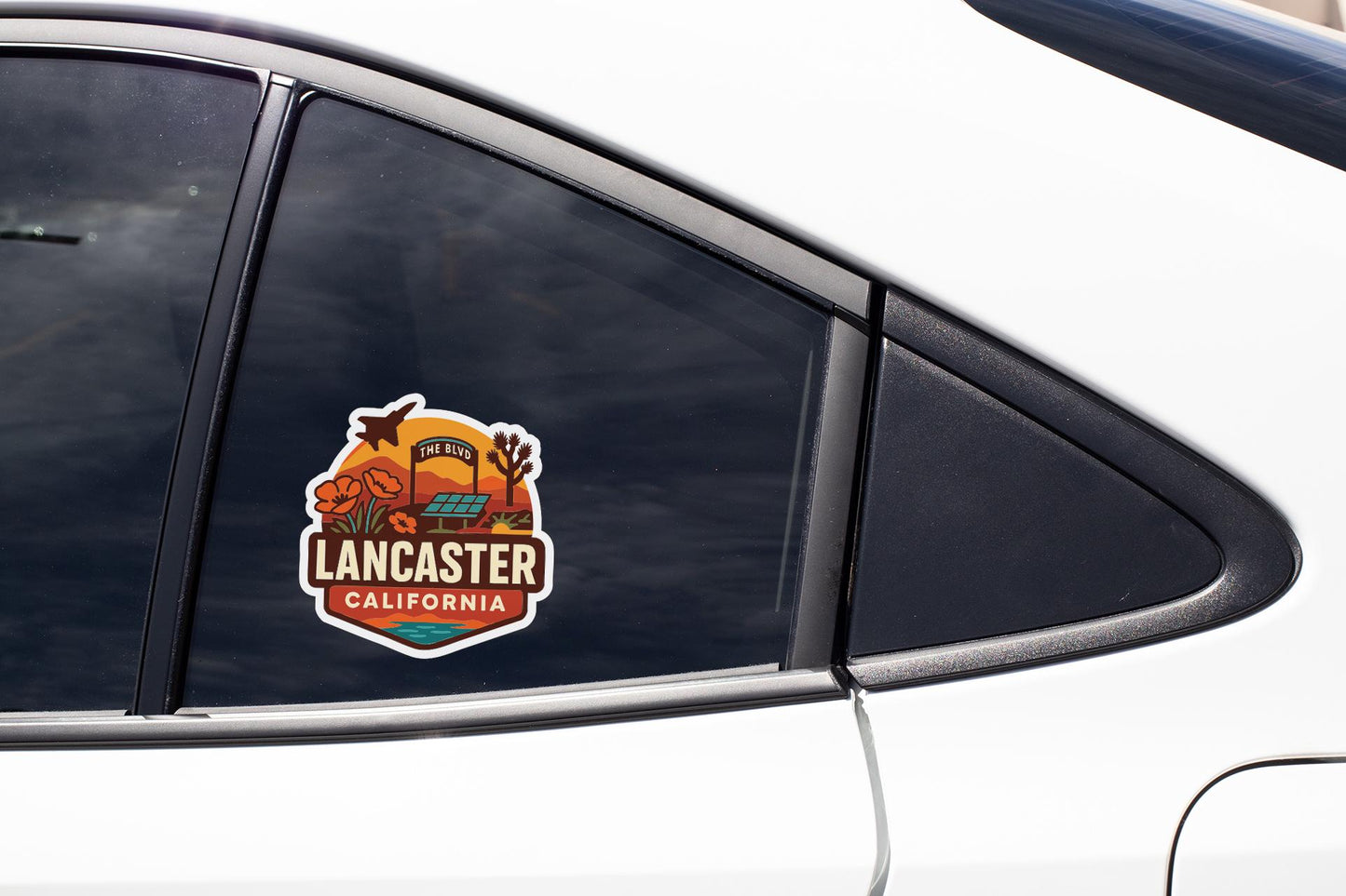 A car window with a sticker that says "Lancaster, California" on it.