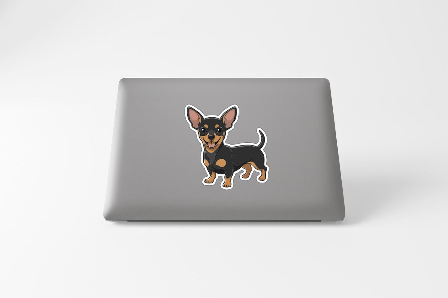 A sticker of a small dog, likely a Chihuahua, is displayed on the back of a laptop computer.