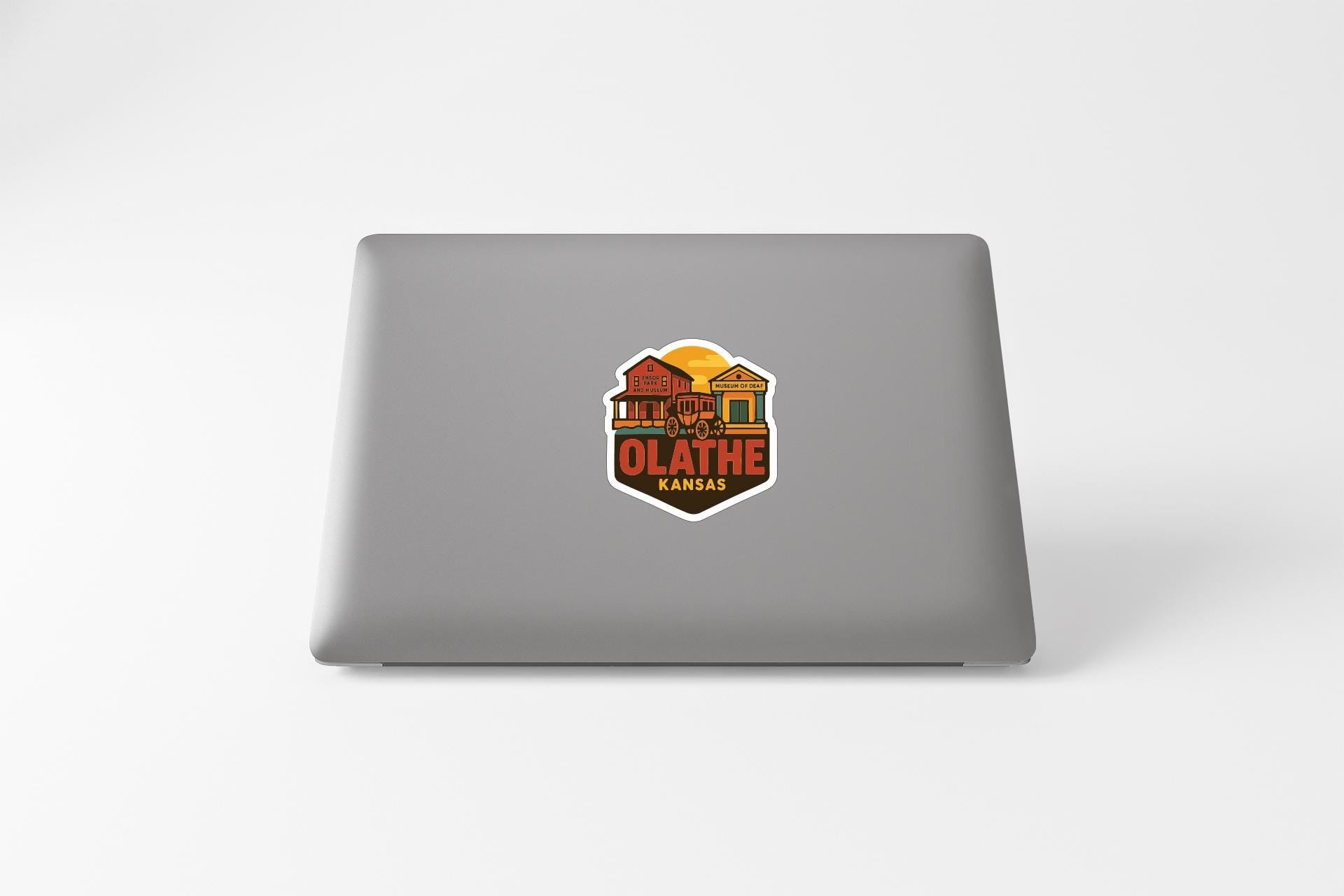 A sticker on the back of a laptop, depicting a house with a sun in the background.