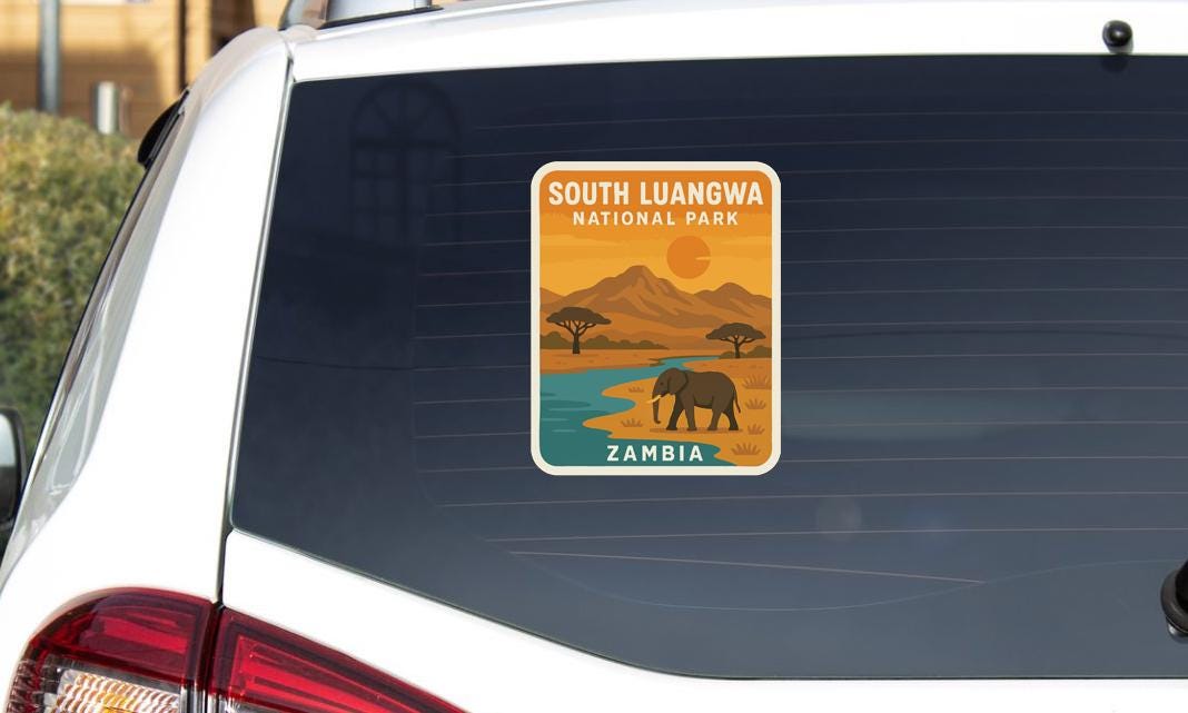 a sticker on the rear window of a car, depicting a scenic landscape with a river, mountains, and an elephant.