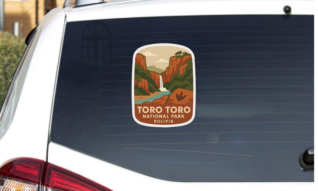 A sticker on the rear window of a car, depicting a scenic landscape with mountains, a waterfall, and a river.
