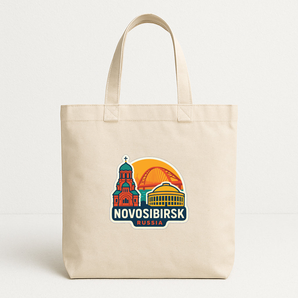 A beige tote bag with a graphic design featuring a building and a sun-like symbol, along with the text "NOVOSIBIRSK RUSSIA".