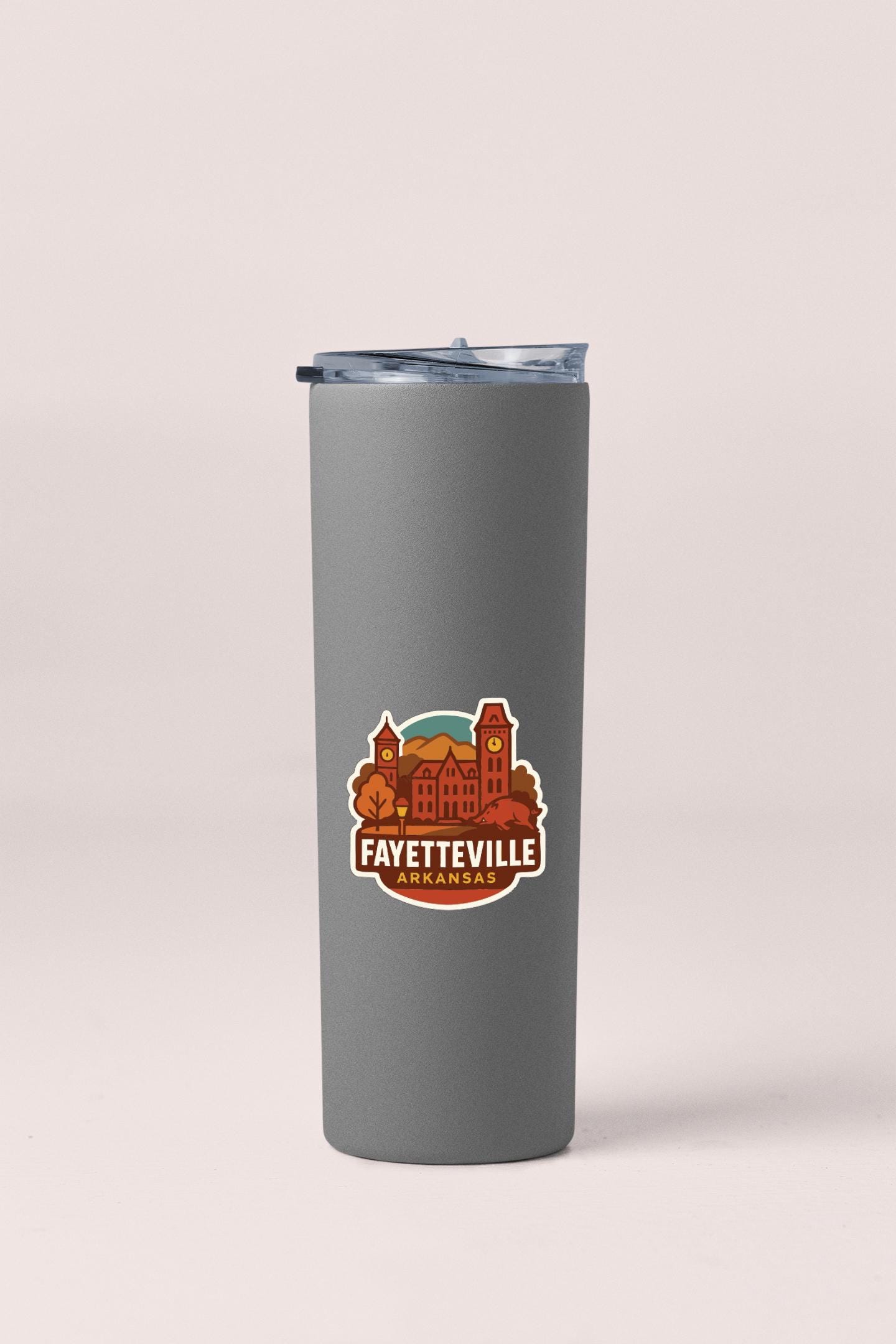 A gray insulated tumbler with a lid and a sticker featuring an illustration of a cityscape.
