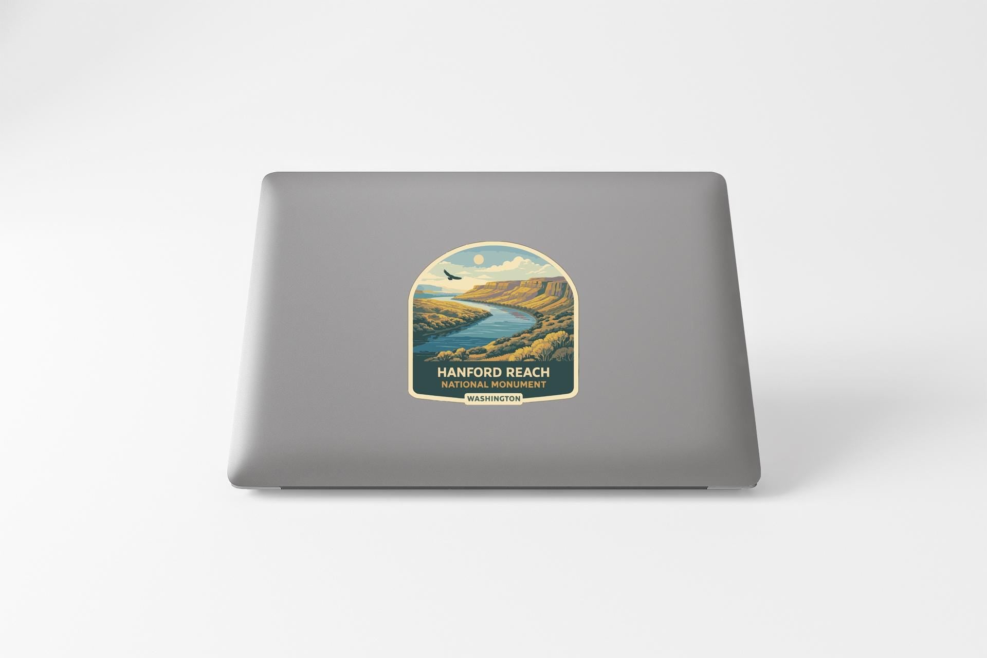 A sticker on the back of a laptop, depicting a scenic landscape with a river and mountains.