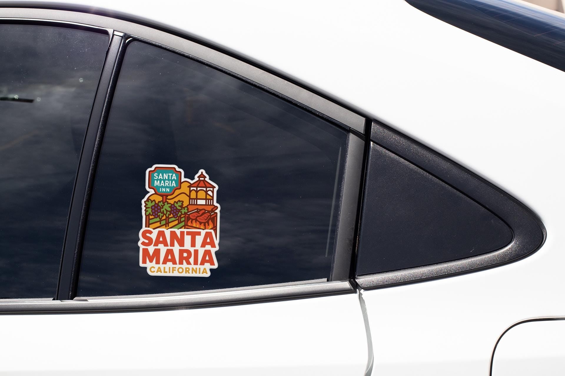 A car window with a sticker on it, featuring an illustration of Santa Maria, California.