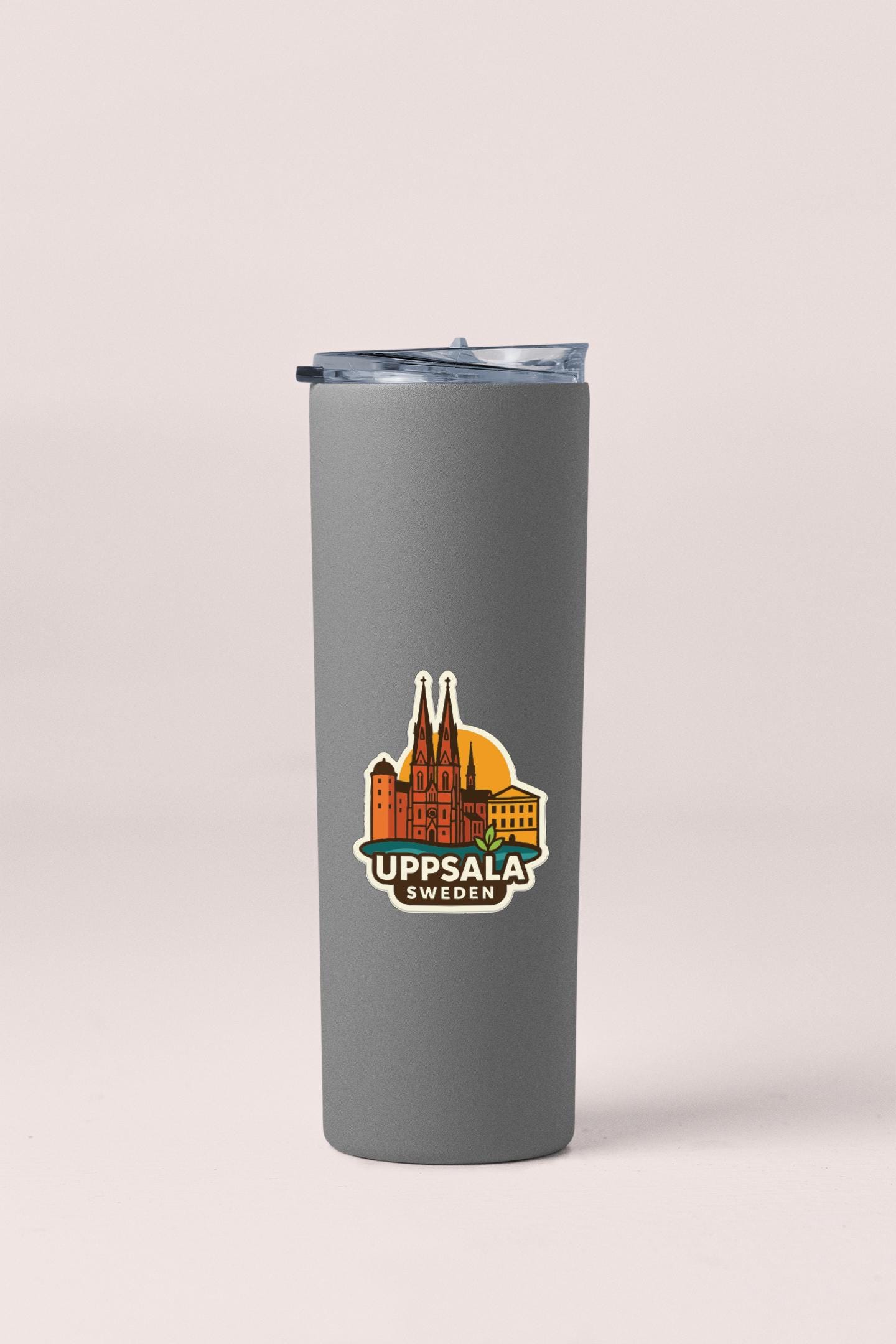 A gray insulated tumbler with a lid and a sticker depicting the Uppsala Children's Hospital in Sweden.