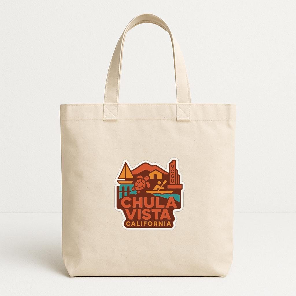 A beige tote bag with a colorful graphic design featuring a beach scene, mountains, and a surfboard, along with the text "CHULA VISTA CALIFORNIA".
