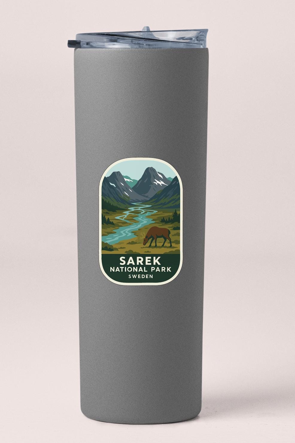 A gray cylindrical container with a label that features an illustration of a mountain landscape with a river and a person walking through it.