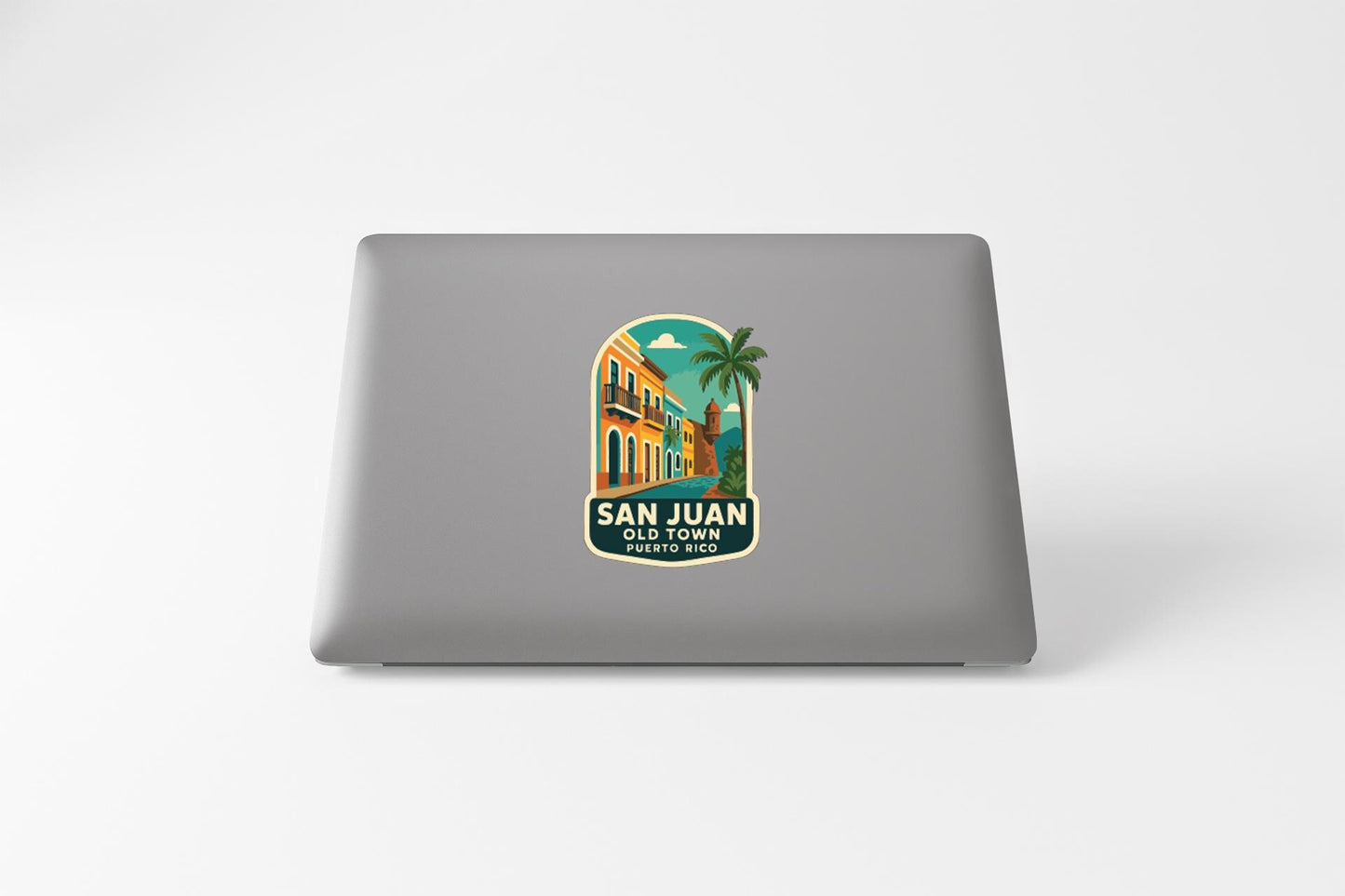 a sticker or decal on the back of a laptop, depicting a tropical scene with a palm tree and a colorful building.