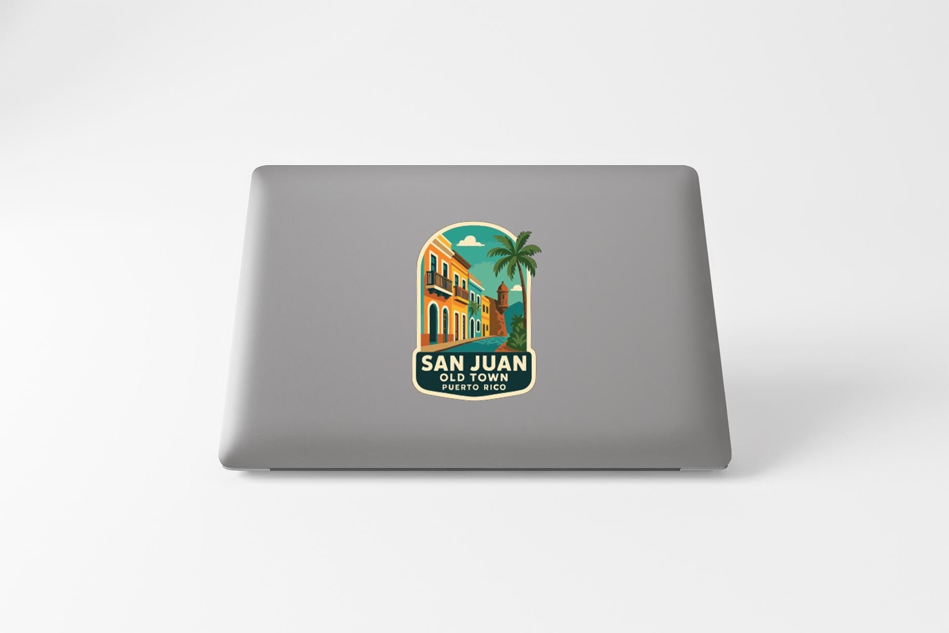 a sticker or decal on the back of a laptop, depicting a tropical scene with a palm tree and a colorful building.
