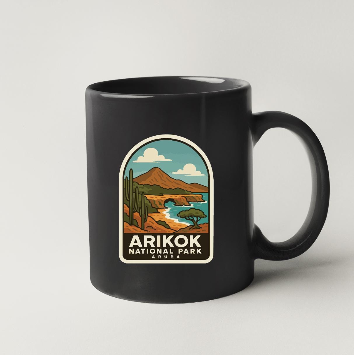 A black coffee mug with a graphic design depicting a desert landscape with mountains, cacti, and a river.