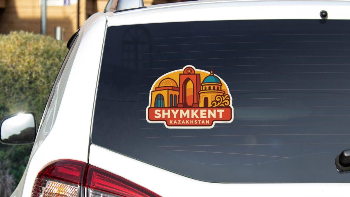 the rear window of a white car with a sticker or decal on it, featuring an illustration of a cityscape with a dome-shaped building.