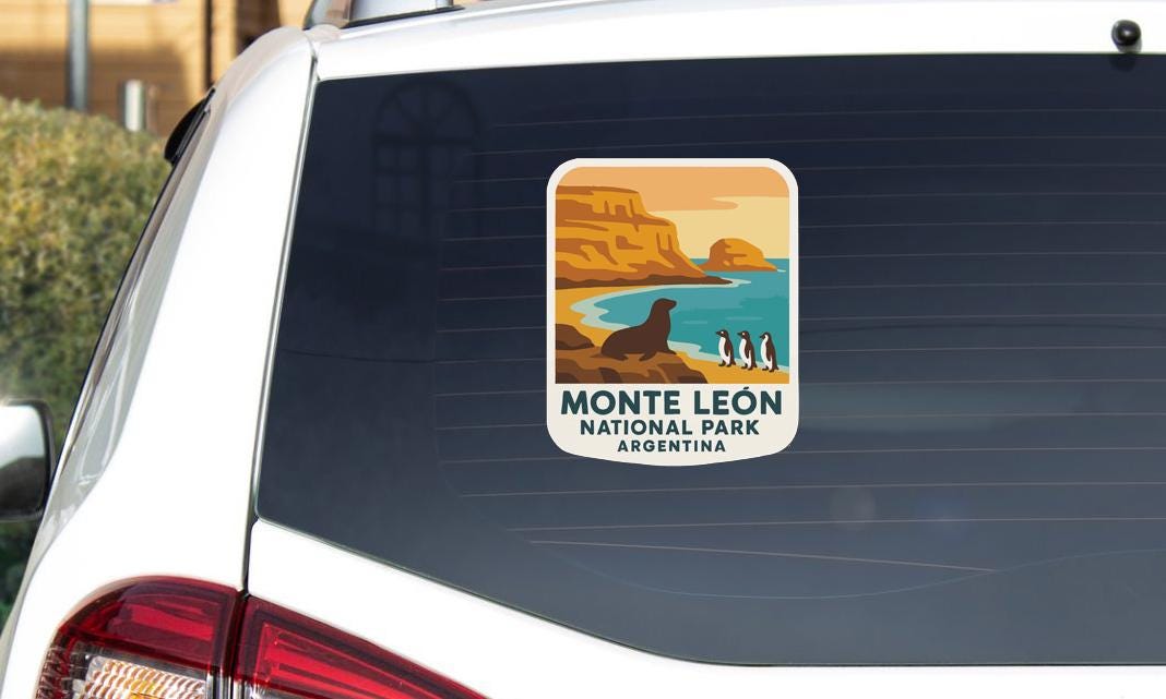 A sticker on the rear window of a car, depicting a scenic landscape with mountains, a beach, and penguins.