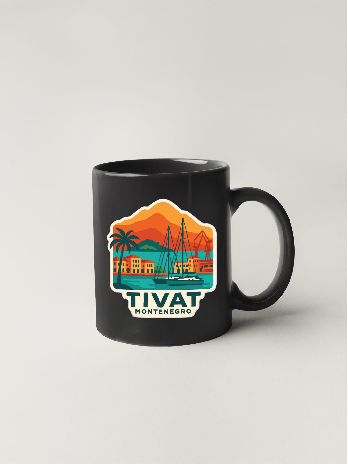 A black coffee mug with a colorful illustration of a coastal town and a sailboat, along with the text "TIVAT MONTENEGRO".