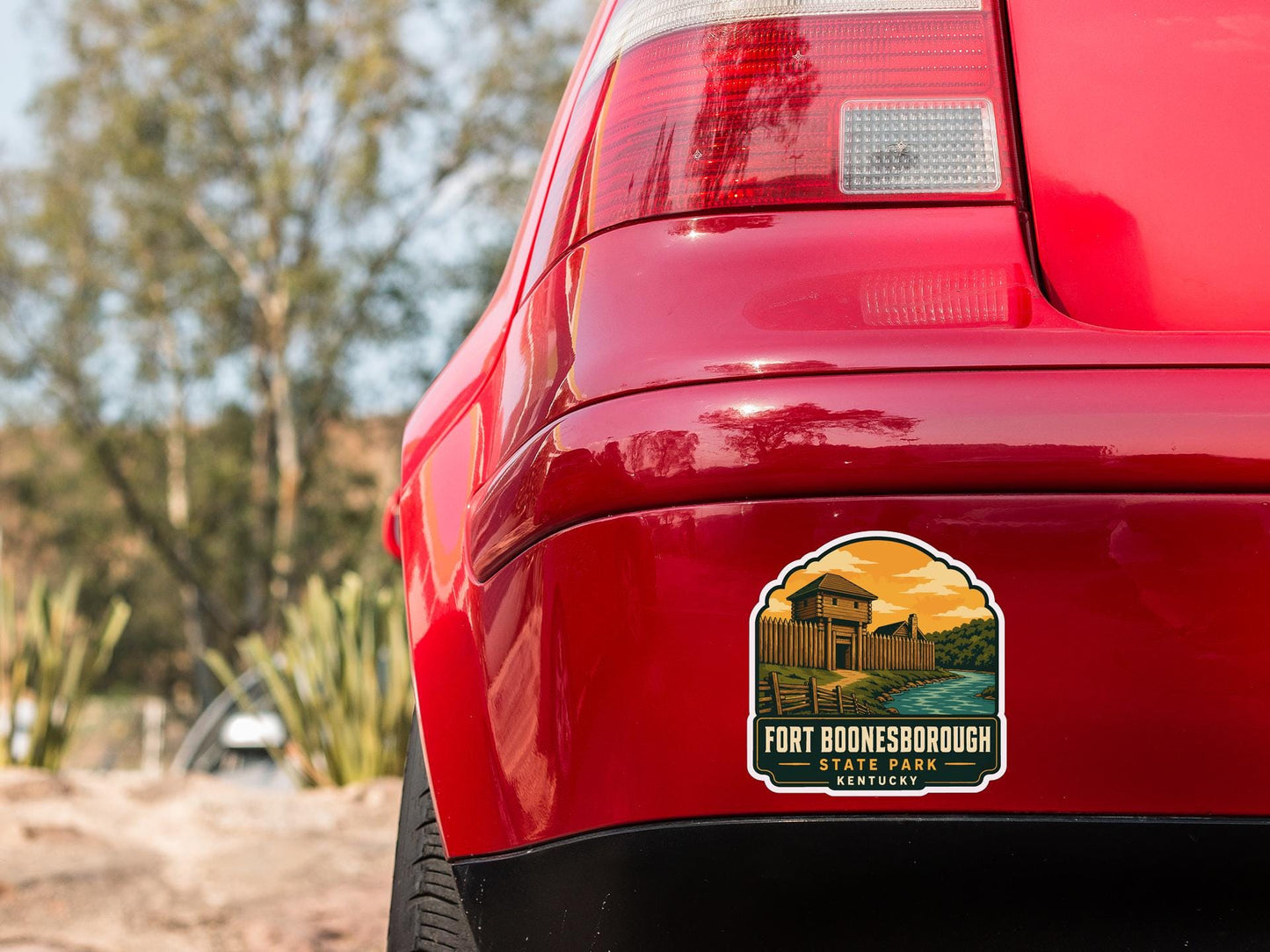 the rear end of a red car with a sticker on the back window that says "Fort Boonesborough State Park, Kentucky".