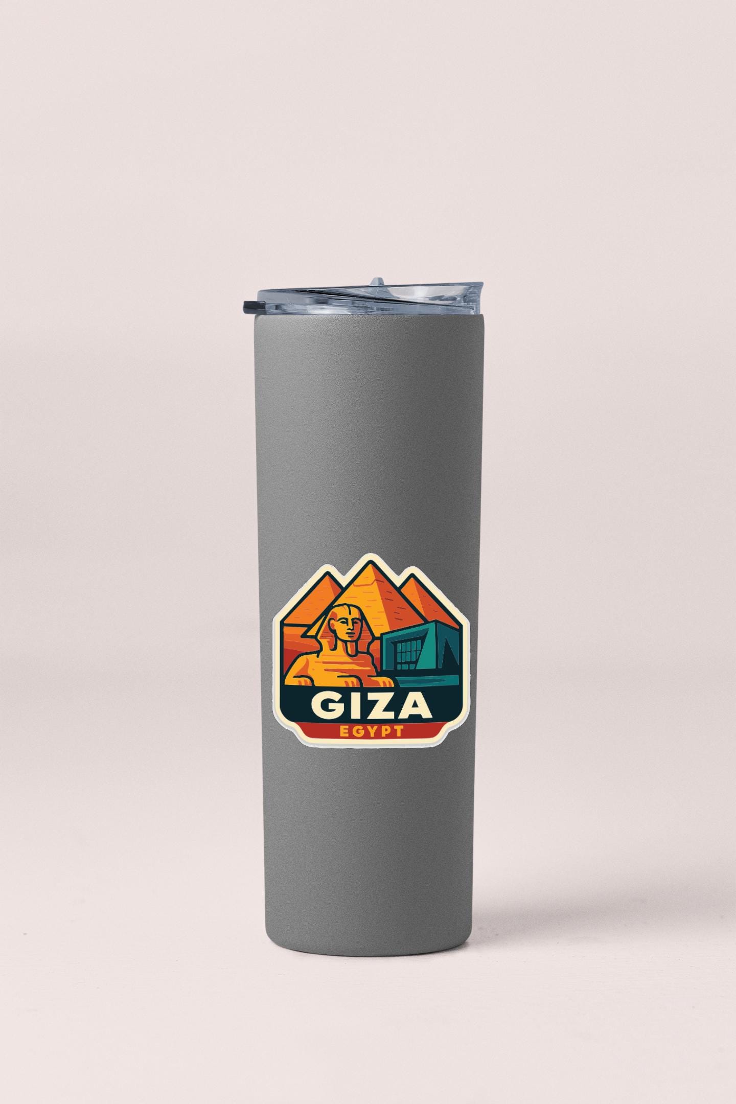 A gray insulated tumbler with a sticker featuring an illustration of the pyramids of Giza in Egypt.