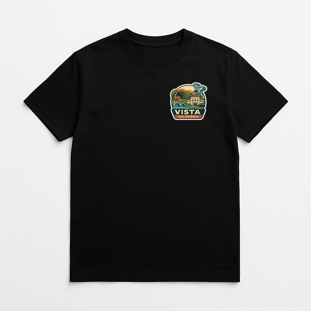 A black t-shirt with a colorful graphic on the front, depicting a scenic landscape with a building and palm trees.