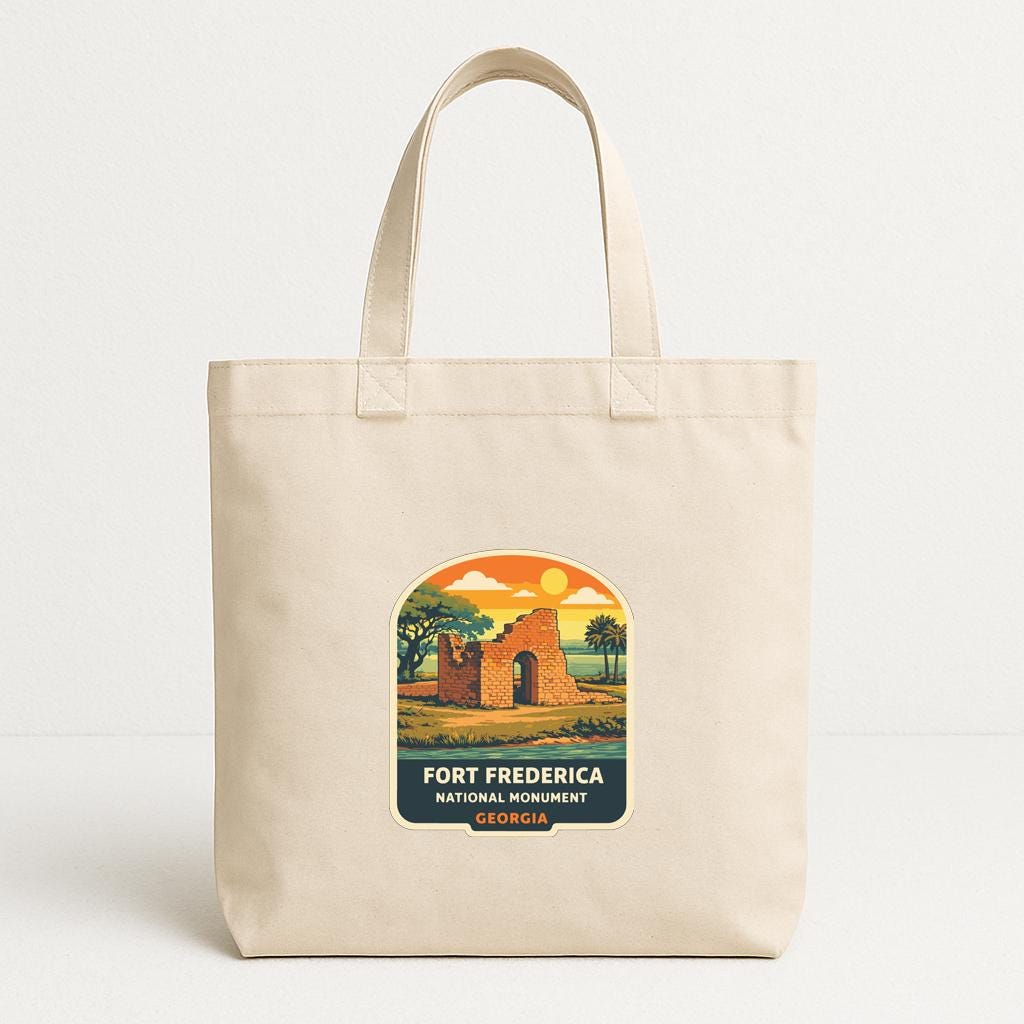 A beige tote bag with a printed label that says "FORT FREDERICA NATIONAL MONUMENTOS, GEORGIA".