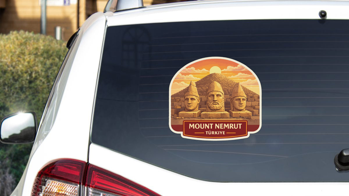 a sticker on the rear window of a car, depicting three stone statues or monuments, with the text "Mount Nemrut" and "Turkye" written below them.