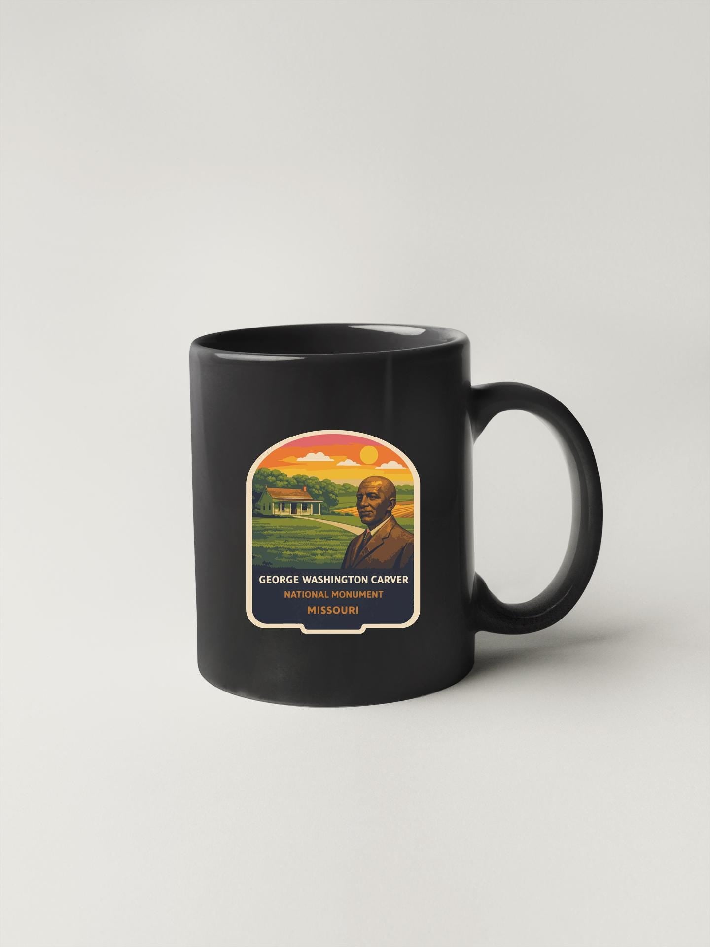 A black coffee mug with a graphic design featuring a portrait of a man and the text "GEORGE WASHINGTON CARVER NATIONAL MONUMENT MISSOURI".
