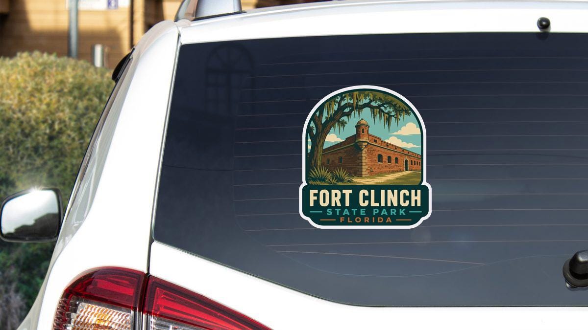 A sticker on the rear window of a white car, depicting Fort Clinch State Park in Florida.