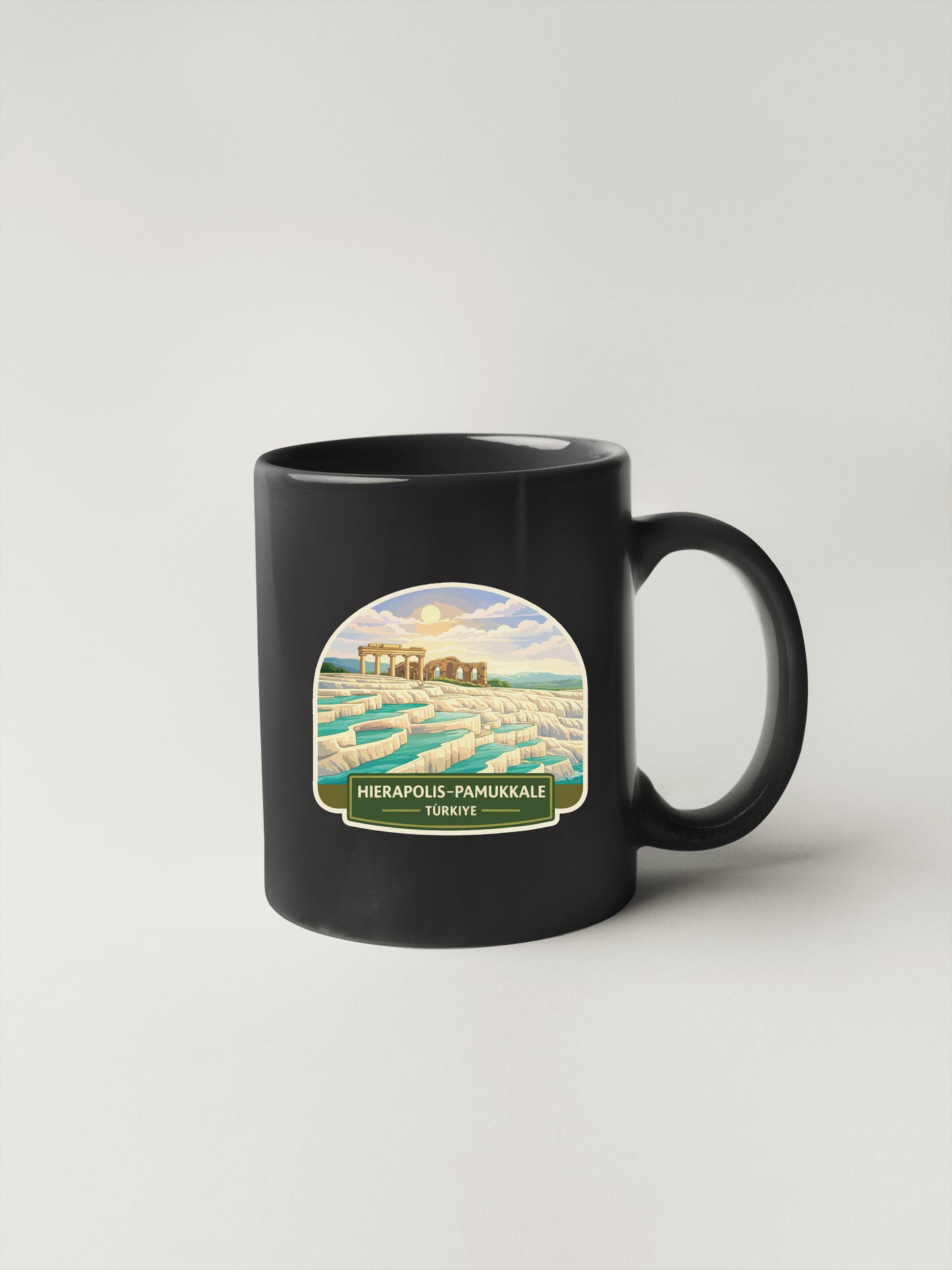 A black coffee mug with a label depicting the ancient city of Hierapolis-Pamukale in Turkey.