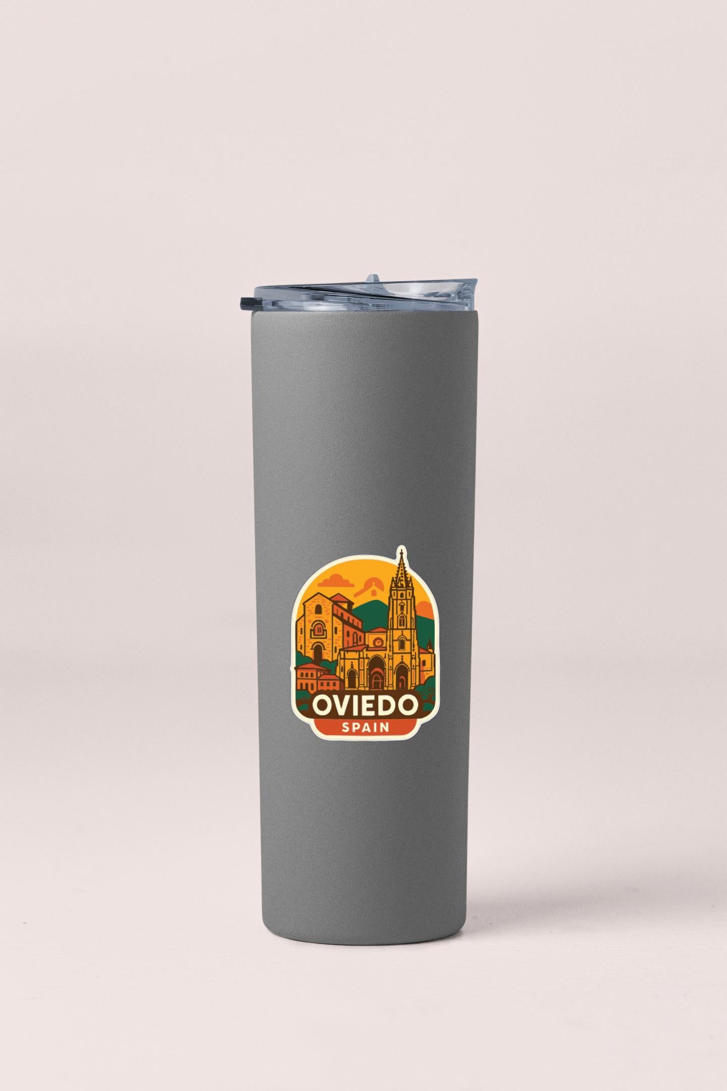 A gray insulated tumbler with a sticker depicting the city of Oviado, Spain.