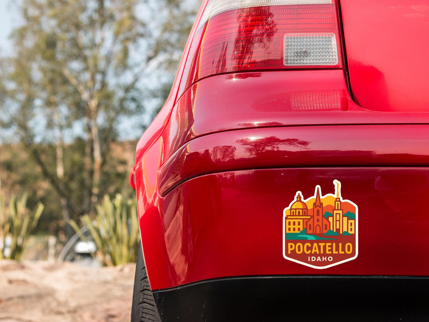 the rear end of a red car with a sticker on the trunk that says "POCATELLO IDAHO".