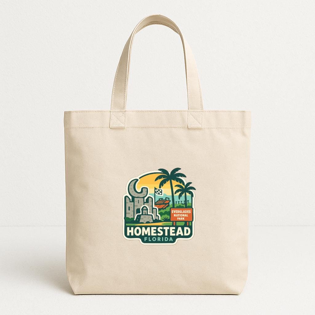 A beige tote bag with a graphic design featuring a palm tree, buildings, and text that says "HOMESTEAD FLORIDA".