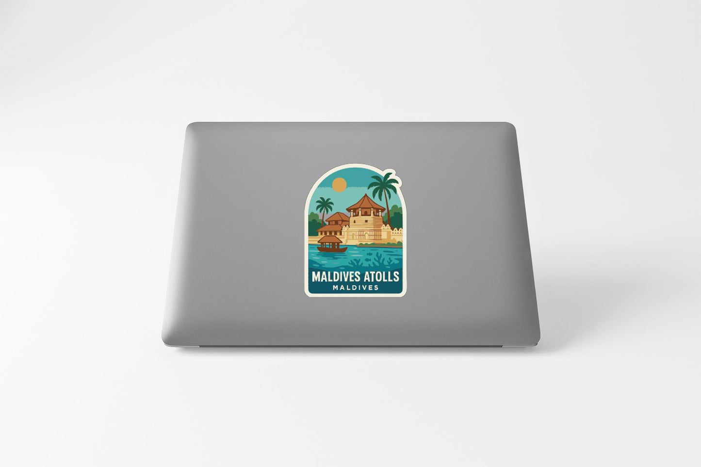a sticker or decal on the back of a laptop, depicting a tropical island scene with palm trees, a building, and a body of water.