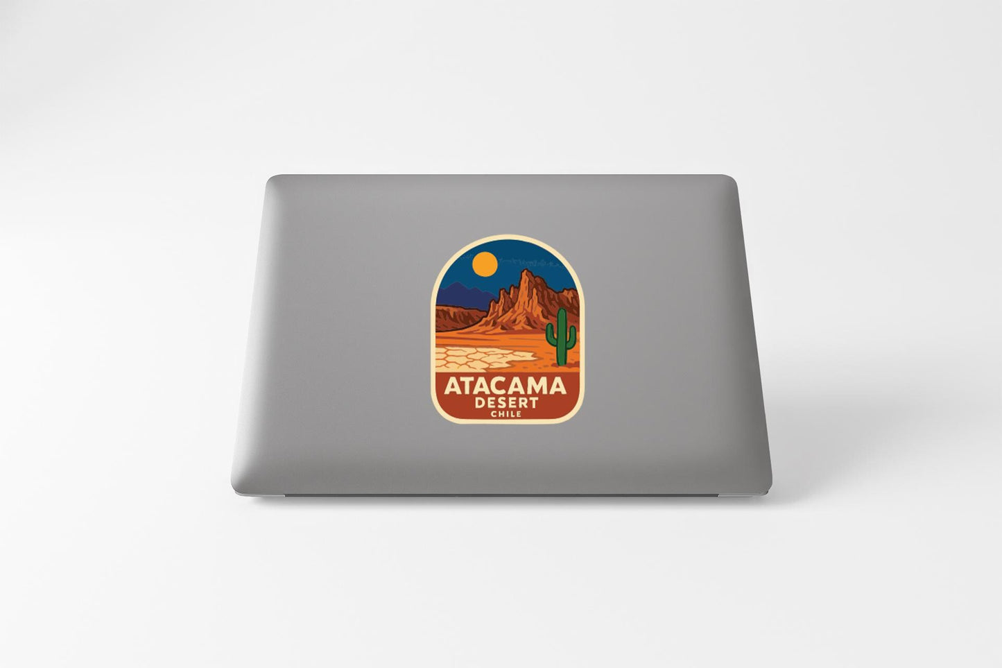 a sticker or decal on the back of a laptop, depicting a desert landscape with a cactus and mountains in the background.