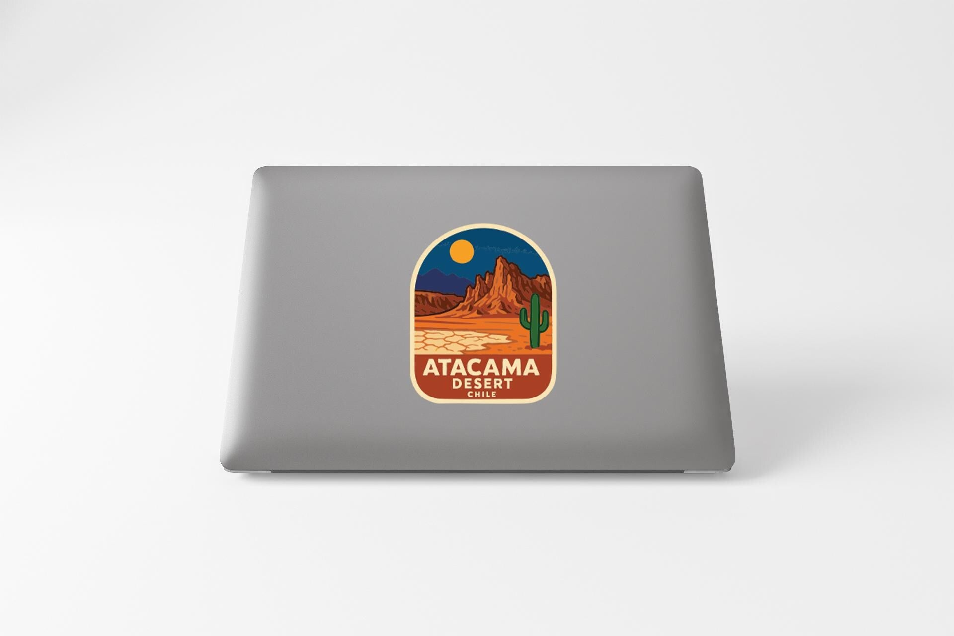a sticker or decal on the back of a laptop, depicting a desert landscape with a cactus and mountains in the background.