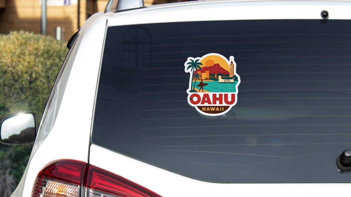 A sticker on the rear window of a white car, depicting a tropical scene with palm trees, a sunset, and a beach.